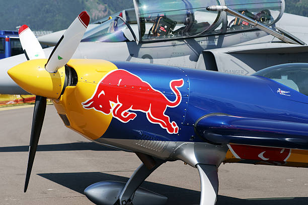 Zeltweg, Austria - July 1, 2011: Front part of Extra 300S aerobatic plane with Red Bull sign on it on display at Airpower 11 air show. Extra 300S is one of the best aerobatic competition aircraft designed by Walter Extra from Germany. In the background canopy of fighter airplane Saab JAS 39 Gripen is visible.