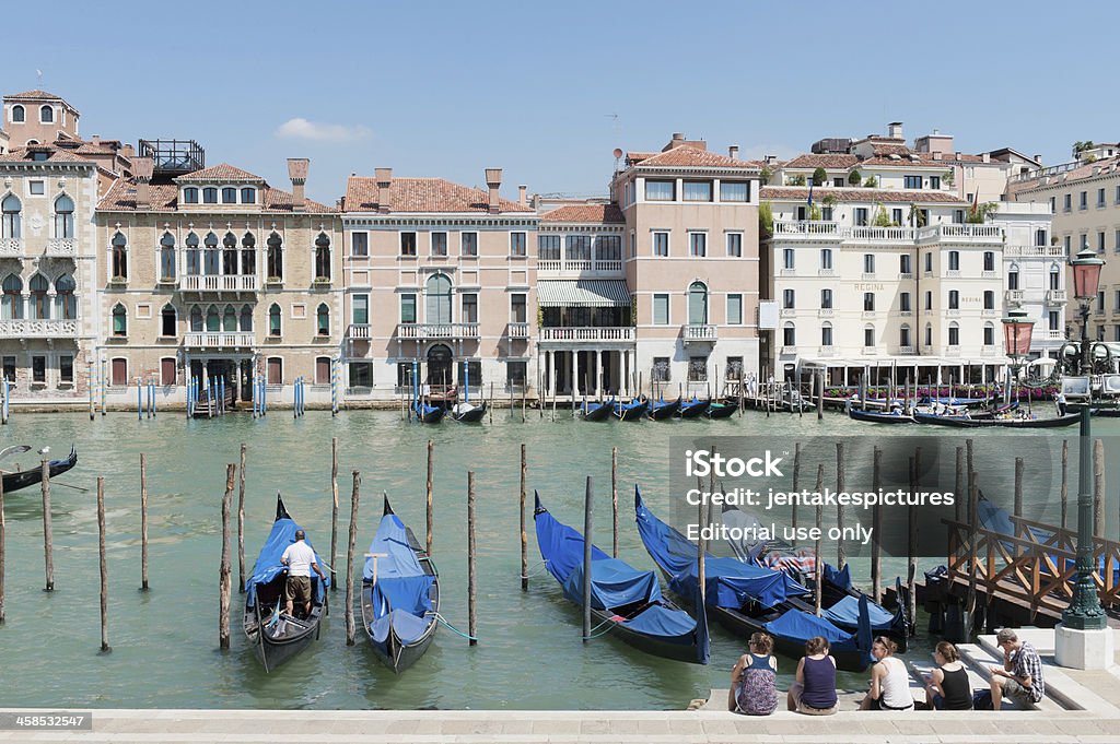 Venice Venice, Italy - June 27, 2011: Tourists sitting on the edge of the Grand Canal in Venice, Italy, outside of Basilica di Santa Maria della Salute. Architectural Feature Stock Photo