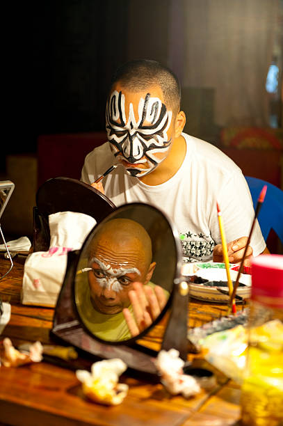 Actors making up at back stage Chengdu, China - July 09, 2011: Sichuan opera actors are making up at the back stage of a traditional tea house in Chengdu, China.Generally, it needs 30 - 60 minutes to complete the whole process. chinese opera makeup stock pictures, royalty-free photos & images