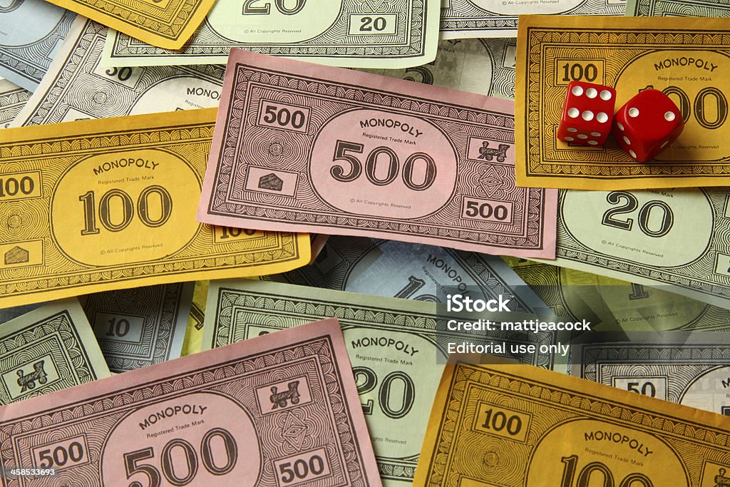Monopoly game money with dice London, United Kingdom - August 4, 2011: Monopoly game money. Monopoly is a board game named after the concept of dominating a market, a monopoly. Players take turns to move around a board buying property and paying and receiving rent. Monopoly Stock Photo