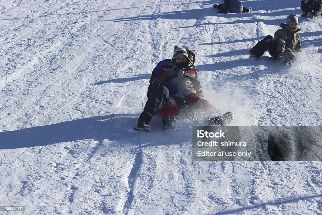 Niños deslizante hacia abajo en la nieve en las montañas de los Andes - Foto de stock de Aire libre libre de derechos