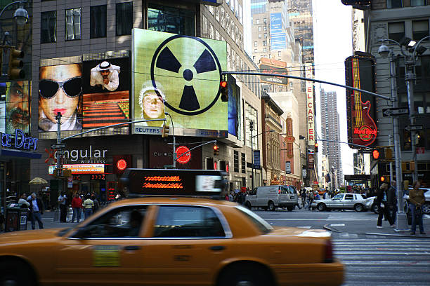 New York, NY, USA - April 30, 2006: street scene on Times Square, pedestrians and yellow cabes in front of billboards with nuclear warning sign next to Arab man and show stars