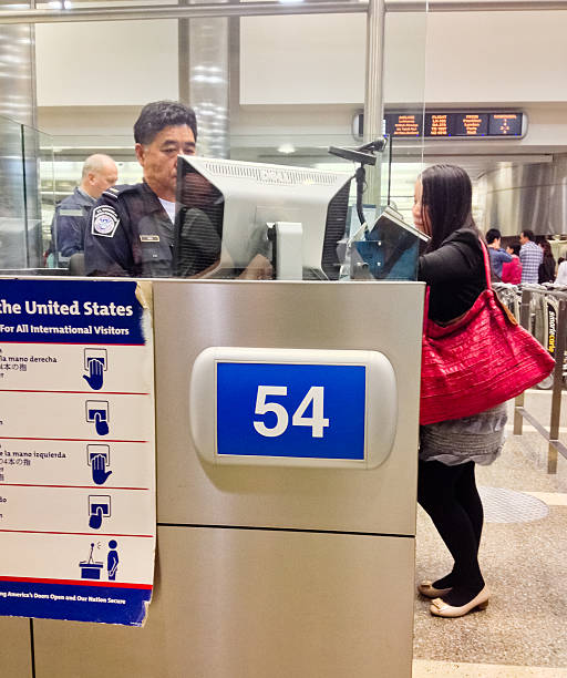 U.S. Immigration officer checking documents of tourists Los Angeles, USA - April 28, 2013: U.S. Immigration officer checking documents Asian tourist arrived in Los Angeles. U.S. Customs at Los Angeles Airport customs agent stock pictures, royalty-free photos & images