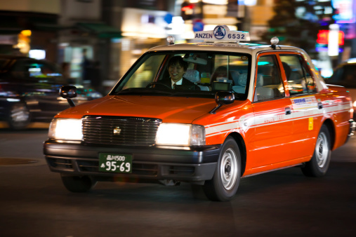 Tokyo, Japan - November 6, 2010: Taxi driver driving customers with taxi at night Hamamatsucho district, Tokyo, Japan.