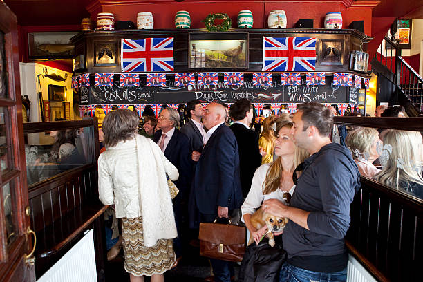 London, United Kingdom - April 29th 2011: Tourists, businessmen and locals crowd \\'Ye Grapes\\' public house in Shepherd Market in London\\'s Mayfair to watch the royal wedding of Prince William to Kate Middleton on the pub\\'s TV screens. The pub, opened in 1882, is adorned with Union Flags and bunting in celebration of the special occasion.