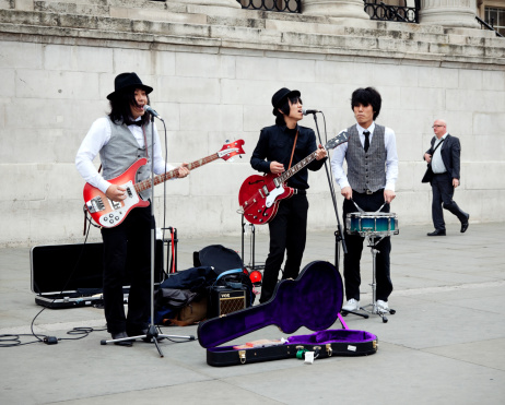 London, England - May 27, 2011: Three young Asian men playing Beatles songs to passers-by outside the National Gallery, in Trafalgar Square, London. This area in front of the National Gallery is very popular with street performers and there is generally something happening there.