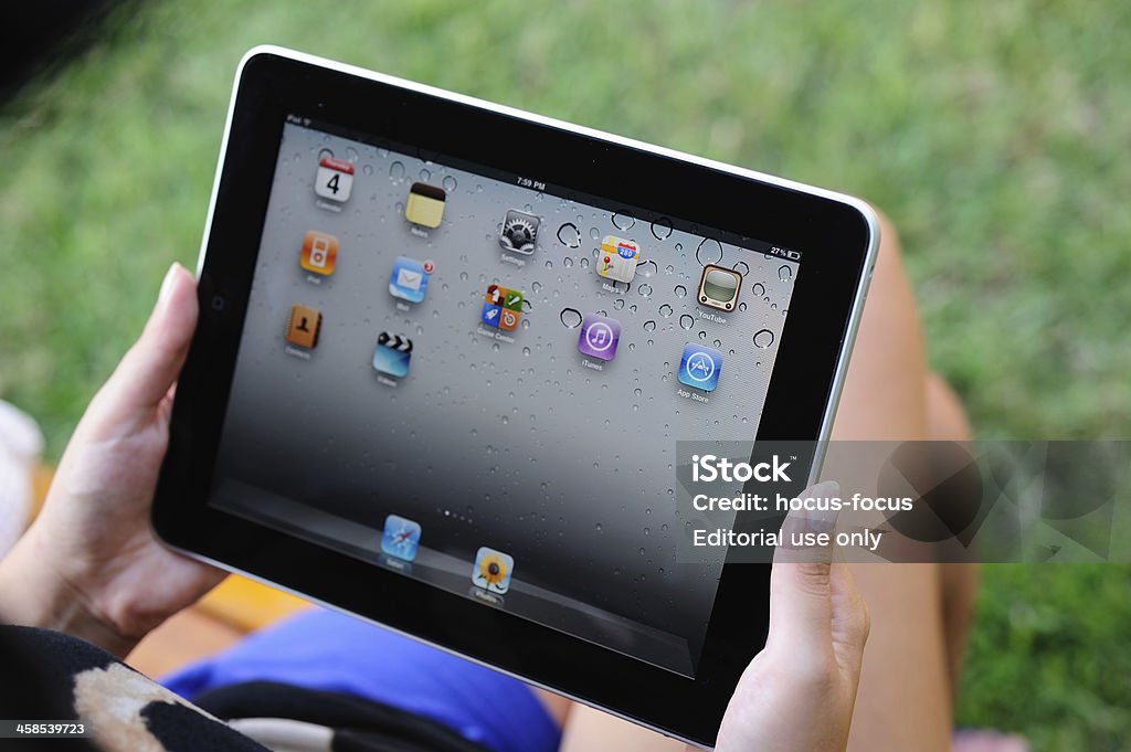 Using iPad in park Astanbul, Turkey - August 3, 2011: Hands holding an Apple iPad in park. The iPad is produced by Apple Computer, Inc. Adult Stock Photo