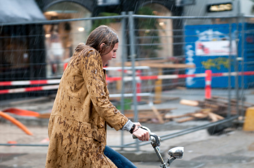 Copenhagen, Denmark - June 17th, 2011: Woman rides a bike as heavy rain come pouring down.  Her hair and jacket gets soaked.