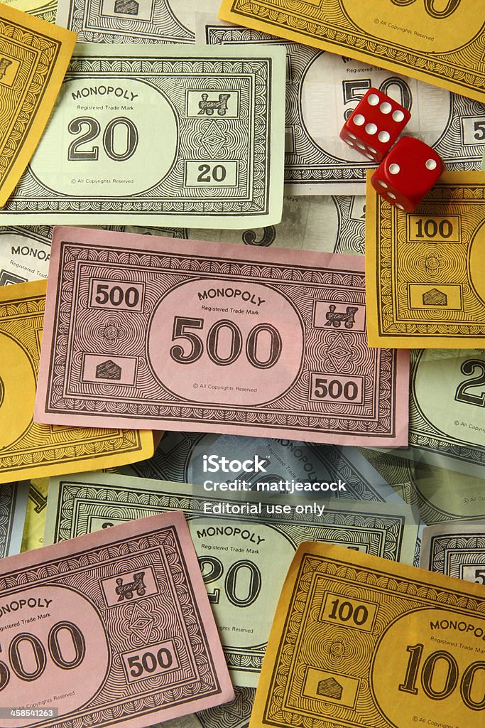 Monopoly game money with dice London, United Kingdom - August 4, 2011: Monopoly game money. Monopoly is a board game named after the concept of dominating a market, a monopoly. Players take turns to move around a board buying property and paying and receiving rent. Arts Culture and Entertainment Stock Photo