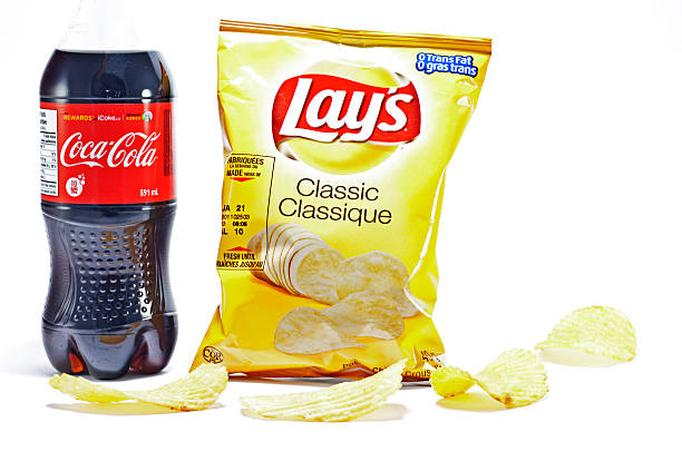 Classic Junk Food Vancouver, Canada - February, 11 2012: Bottle of Classic Coca-cola soft drink and a bag of Classic Lay\'s potato chips shot in studio on white background. lays potato chips stock pictures, royalty-free photos & images