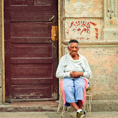 Havana, Cuba - January 1, 2011: Senior woman sitting near the door to her house in Havana Vieja (Old Havana)