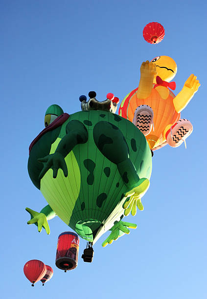 Albuquerque, New Mexico, USA - October 12, 2006:  The frog, scarecrow and Alpo dogfood can special shape hot air balloons rise in dawn sunlight at the Albuquerque International Balloon Fiesta - the largest such festival in the world. It started in 1972 and takes place in early October, lasting 9 days. Starting with just 21 balloons, the number rose to 1019 in 2000 and eventually had to be limited first to 750, then to 600. Over 100 pilots are from foreign countries. The specially shaped balloons are the most popular feature of the festival.  In addition to those in the image, they include a pig, American flag, football, eagle, carousel, cactus, bumble bees, space shuttle, chili ristra, football, daisy, locomotive and many others.  There are also polyhedral shapes and long distance high altitude balloons on hand.