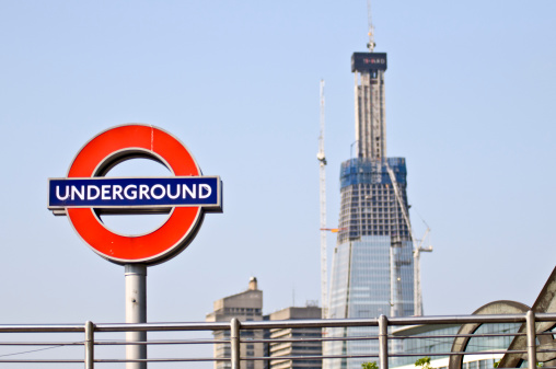 London, UK - April 30, 2011: The London Underground logo, named The Roundel is in the foreground. It's situated at Tower Hill tube station. In the background, there's this new building being constructed, The SHARD. At 310m high, it will be the tallest building in Europe. It should be ready by may 2012. It's situated at London Bridge.