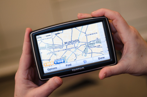 Florence, Italy - March 18, 2011: Woman hand holding a TomTom map with munchen map. TomTom International BV is a Dutch company that makes satellite navigation systems for automobiles, motorcycles, handhelds and smartphones. Each system has a processor and a touch screen. TomTom is the leading supplier of navigation systems in Europe with offices around the world. The model of TomTom is XXL Europe version with 5 inch screen.