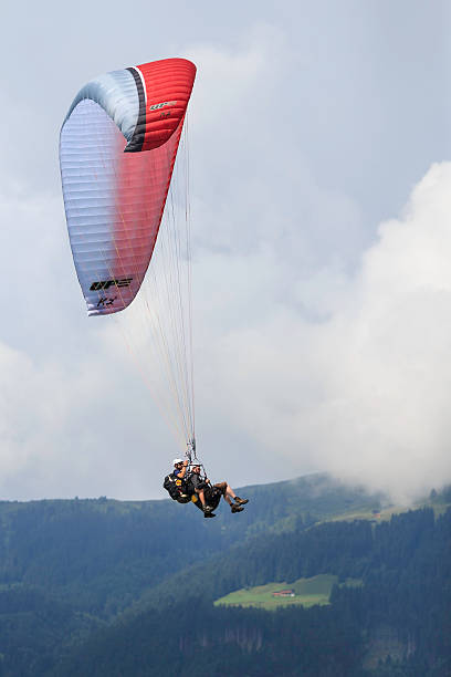 Two men paragliding over Zillertaler alps, Zell am Ziller, Austria Zell am Ziller, Austria - July 10, 2013 : Two men paragliding over the Zillertaler alps, shortly before landing next to the outdoor swimming pool in Zell am Ziller, Austria on a summer day in 2013. zillertaler alps stock pictures, royalty-free photos & images