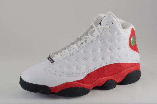 Bergen County New Jersey, USA - September 8, 2013: A Nike Air Jordan XIII in a red, white, and black colorway against a white background. The Nike Air Jordan XIII was inspired by the black panther and features a sole inspired by the animal's paw and a holographic disc below the ankle that ressembles a cat's eye. Originally released in 2010, the Air Jordan XIII was re-released in 2004, 2005, 2008, 2010, 2011, and 2013.