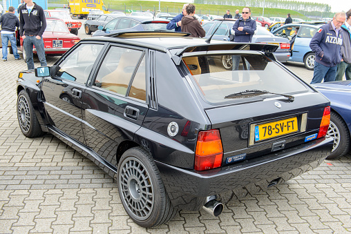 Assen, The Netherlands - May 19, 2013: Black Lancia Delta HF Integrale classic car parked in the paddock during the 2013 Viva Italia event at the Assen TT circuit. People in the background are looking at the cars.