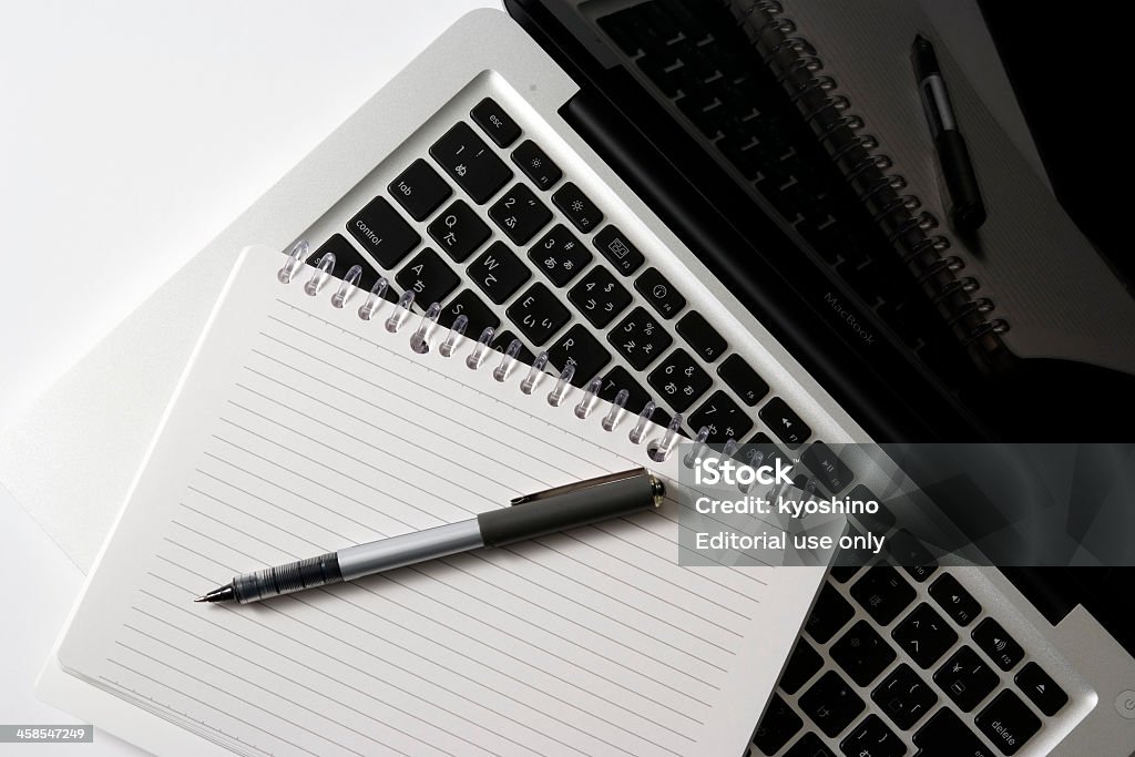 Apple MacBook Tokyo, Japan-November 21,2010 MacBook,Spiral Notebook and pen on 13-inch Apple MacBook isolated white background. A keyboard for Japan. Computer Monitor Stock Photo