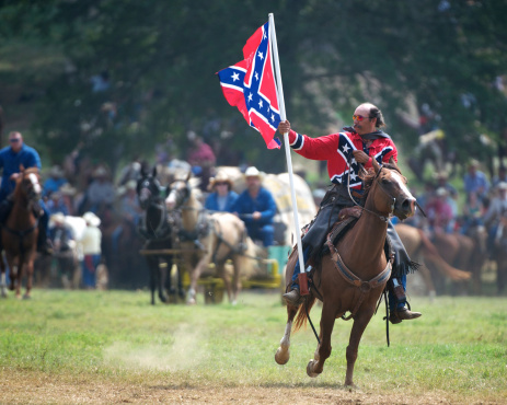 Clinton, Arkansas, USA, September 3, 2011: A man on horseback waves a Confederate flag at the spectators as part of the opening ceremonies at the National Championship Chuckwagon Races, an annual event near Clinton, Arkansas.
