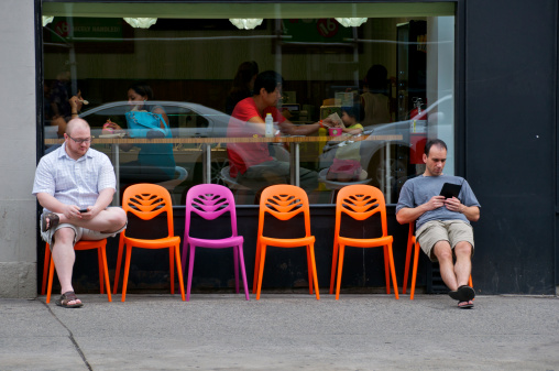 New York City, USA - July 24, 2011: Customers seated inside a frozen yogurt shop along Amsterdam Avenue are seen eating as two men using hand held personal communication devices sit outside the storefront, Upper West Side of Manhattan.