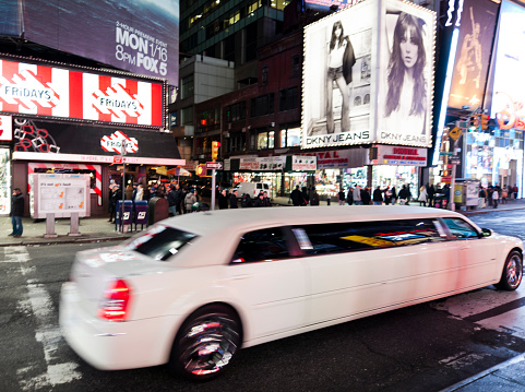 New York, United States - January 11, 2012: Limousine and people at Times Square at night.. At the junction of Broadway and the 7th avenue is brightly lit by neons and billboards and part of the theater district in Manhattan. It is also one of the main tourist attractions of the city.