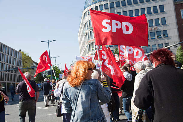international worker's day demonstration Dortmund, Germany - May 1, 2011: international worker's day demonstration, red head woman with flag of SPD at May demonstration. SPD is a left wing political party in Germany. On 1st May, there is a demonstration of different unions and political parties in Dortmund. It is tradition in Germany to celebrate the international workerâ german social democratic party photos stock pictures, royalty-free photos & images