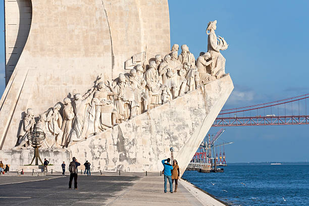 Lisbon, Portugal - December 15, 2011: Tourists are taking photos in front of the Monument to the Discoveries on the riverside of the River Tagus (Tejo) in Lisbon, Portugal. The Monument to the Discoveries was inaugurated in 1960 during celebrations of the 500 year anniversary of the death of the Infant Henry the Navigator. The monument is a symbol for many relevant heroes of Portuguese history  par example Vasco da Gama. On the top of the monument Henry the Navigator is holding at his hands a small caravel which remembered in history of the of Portugal as maritime and seagoing nation.