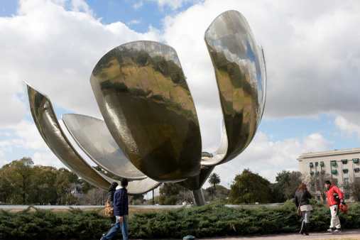 Buenos Aires, Argentina - August, 3 2010: Floralis Generica a working metal sculpture in the United Nations Square opens and closes its petal based on the incidence of solar rays. The images features a few passers by admiring the sculpture
