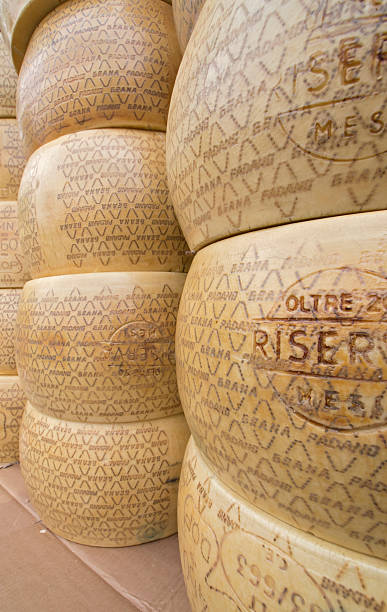 Big rounds of Italian cheese Sal&amp;amp;ograve;, Brescia, Italy - May 14, 2011: Big stock of Italian cheese wheels exposed on  the street market stalls of Sal&amp;amp;ograve;: once passed the quality tests, Grana Padano is fire-branded with its trademark, which also attest its Protected Geographical Status grana padano stock pictures, royalty-free photos & images