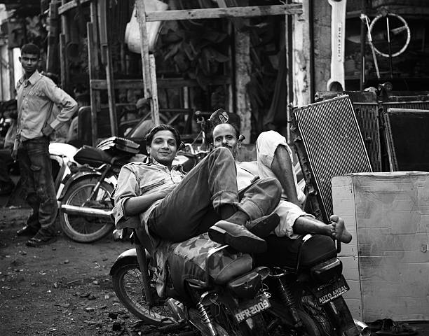 Karachi, Pakistan - June 17, 2010: Mechanics resting after days' work over motorbikes outside the repair garage cum shop of used machinery in Shershah Kabari Market (scrapyard) in Karachi, Pakistan. Located in old city area of metropolis Shershah's junkyard is home of few hundreds shops dealing in scrap items ranging from auto parts to industrial junk imported from developed world to recycle in foundries or to give another lease of life through this market.