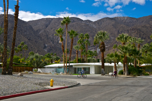 Palm Springs, California, USA - January 15, 2012: Two women are seen riding bicycles along a residential street on a warm, sunny day during winter in the Southern California desert, Coachella Valley.