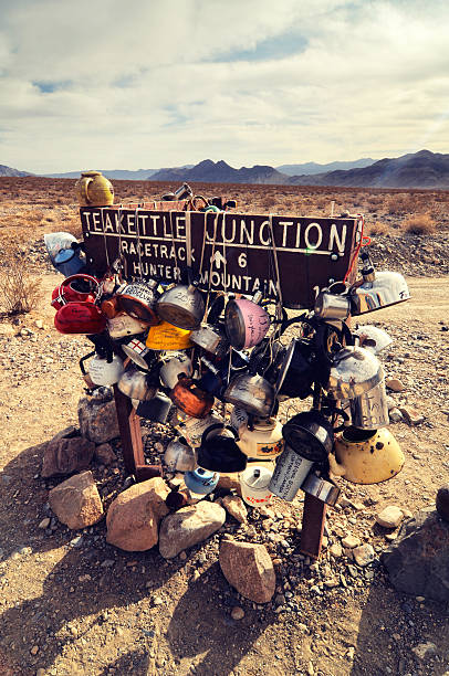 Daylight landscape at Teakettle Junction, Death Valley, USA Death Valley National Park, California, USA - March 29, 2012: Daylight landscape at Teakettle Junction, Death Valley, Inyo County, California, USA. At the junction where the road from Ubehebe Crater meets roads to the Racetrack Playa and Hunter Mountain, there is a sign reading "Teakettle Junction," with many teakettles that visitors have attached to it, with messages written on them. teakettle junction stock pictures, royalty-free photos & images