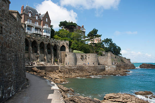 Dinard - Coastal Path Dinard, France - August 08, 2011: A view of costal path from the walkway. Upper on the hill many old villas. On background people are walking on pedestrian way ille et vilaine stock pictures, royalty-free photos & images