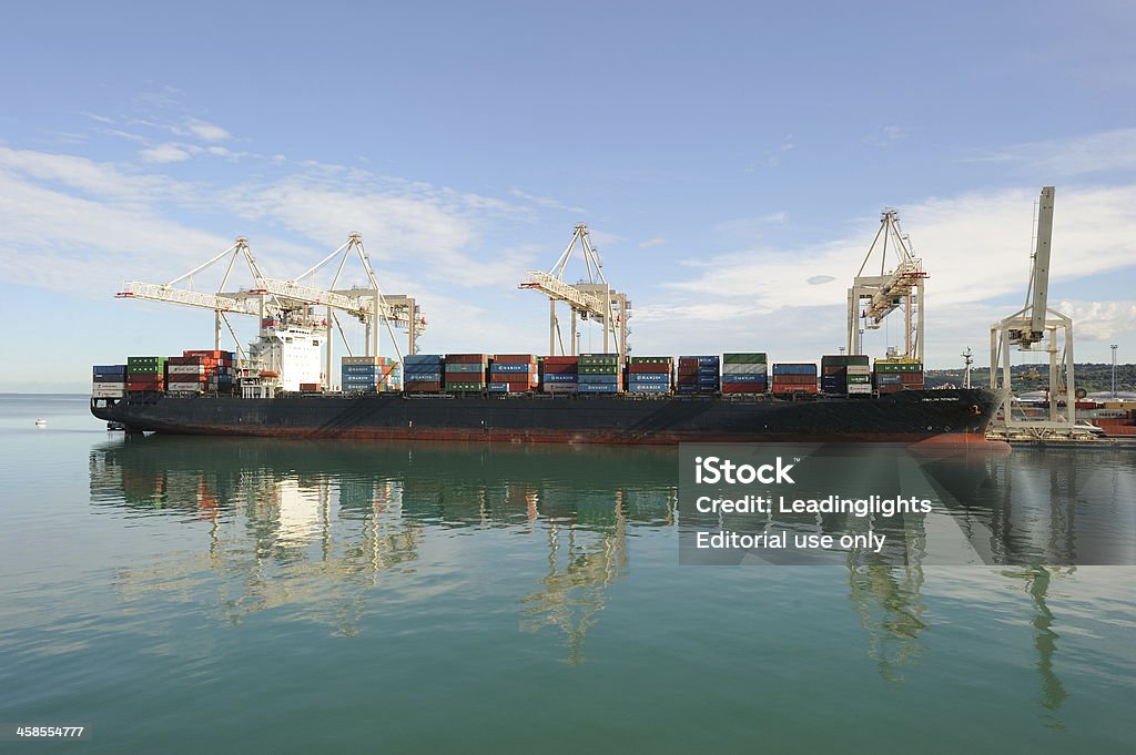 Container ship loading in Slovenia Koper, Slovenia - July, 25 2010: Overhead cranes loading shipping containers on to a cargo ship at Koper, the chief port of Slovenia. The ship is the \'Hanjin Mundra\', registered in Germany. Blue Stock Photo