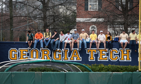 Atlanta, Georgia USA - February 18, 2011: College students sit on a wall outside Georgia Tech baseball stadium watching a game