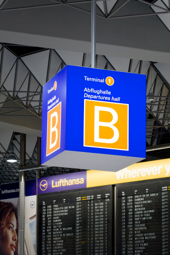 Frankfurt, Germany - March 19, 2011: Large cubical information sign that displays the name of the location: Air Terminal 1, departure hall B at Frankfurt International Airport. In the background a flight plan board
