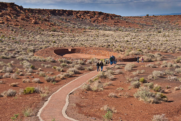 Visitors Walk to the Ball Court Near Wupatki Pueblo Wupatki National Monument, Arizona, USA - May 19, 2011: In addition to the dwellings at Wupatki Pueblo there is a ceremonial ball court. Pictured here are some visitors walking toward the ball court. chinle formation stock pictures, royalty-free photos & images
