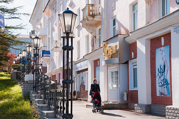 Magadan, Russia - September 14, 2013: Autumn in the city. Almost deserted streets. A young mother with a baby in a stroller walking on the sidewalk.
