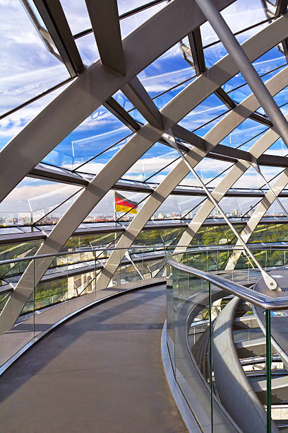 Berlin, Germany - September 08, 2013: Reichstag glass dome construction above German parliament (Bundestag). It is the most visited attraction in Berlin, it has a 360 degrees view of the surrounding Berlin cityscape. Construction of cupola (designed by architect Norman Foster) was finished in 1999, the seat of Bundestag was transfered here also same year. In this photo are detail of the Reichstag dome and flag of Germany.