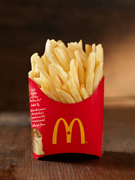 McDonalds French Fries Calgary, Canada - March 15, 2011: McDonalds Medium size French Fries. Shot in a photography studio on a wood table. MCDONALDS FRIES stock pictures, royalty-free photos & images