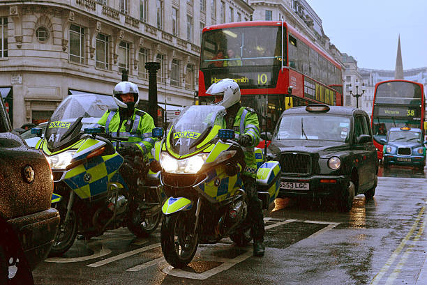 London traffic London, UK - October, 16th 2013:Police motorcyclists, taxi cabs and buses wait in rainy Regent street traffic metropolitan police stock pictures, royalty-free photos & images
