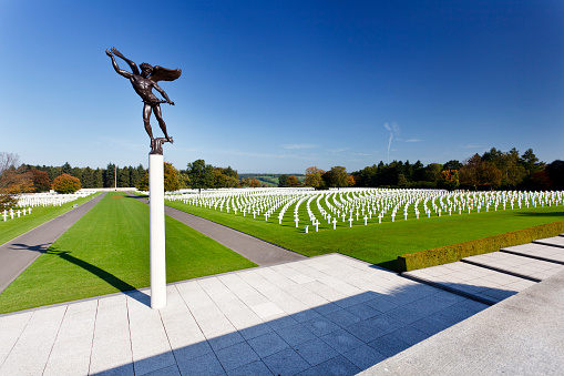 Aubel, Belgium - October 8, 2010: View over the American military cemetery Henri-Chapelle, in front the statue Angel of Peace, the background showing thousands of white crosses for the fallen soldiers