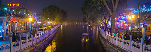 Beijing, China - 30th September 2013: Colourful neon signs illuminating the restaurants and bars lining the crowded shores of Houhai Lake, the popular night life district of Beijing, China's vibrant capital city. Composite panoramic image created from eight contemporaneous sequential photographs.