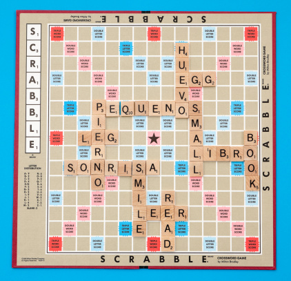 Chillicothe, Ohio, USA - April 13, 2011: Milton Bradley Scrabble board, manufactured by Hasbro, with the letter tiles spelling out various pairs of words.One of the word pairs is in Spanish and the other is its English translation. Playing Scrabble with this bi-lingual twist is a fun way to learn a new language.