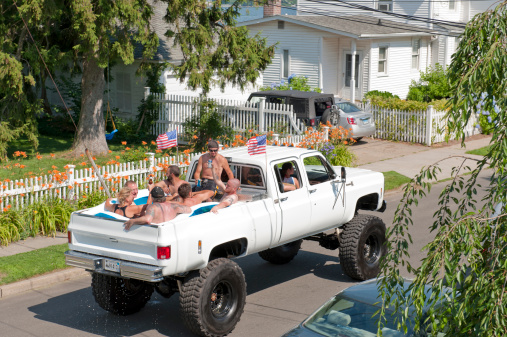 Milford, CT, USA - July 4, 2011: Seven people ride in the back of a large pick-up truck filled with water in Milford, CT. It's July 4th, Independence Day in America, and they are drinking beer and having fun on the summer holiday.