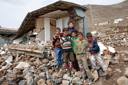 Elazig, Turkey - April 01, 2010 : Turkish children stand together on the debris of a house in their village of Kovancilar in Elazig province, which was destroyed by the earthquake.In the background more damaged houses are visible.The 2010 Elazig earthquake was a 6.1 Mw earthquake that occurred on 8 March 2010, almost flattening entire villages in the province and killing many.