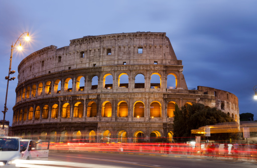 The Colosseum is an icon of travel and tourism with people visiting both day and night. This image shows the busy place with a bus stop, taxis, car lights, street vendors and tourists.Image taken September 26, 2010 in Rome, Italy.