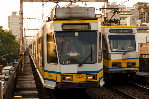 Manila, Philippines - April 19, 2012: LRT light rail transit system stop in metro Manila. Two trains pass each other. The driver of the approaching vehicle can be seen through the glass.