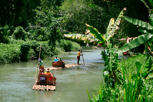 Martha Brae, Jamaica - April 6, 2011: Tourists taking a trip on bamboo rafts at Martha Brae River. The journey takes about 90 minutes on 8m long bamboo rafts, each carrying one or two passengers and a guide. This is one of the most popular tourist destinations in Jamaica.