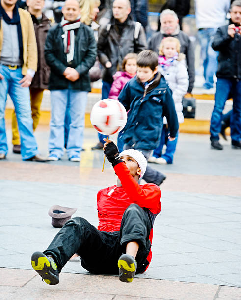 Paris, France - December 28, 2012: Street Performance on Paris street and crowd of spectators. Young Black man playing with ball and raising money from people enjoying the show.